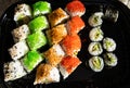 Close-up of sushi rolls with red caviar, salmon, tuna, and avocado isolated on black background. Royalty Free Stock Photo