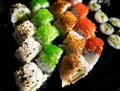 Close-up of sushi rolls with red caviar, salmon, tuna, and avocado isolated on black background. Royalty Free Stock Photo