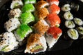Close-up of sushi rolls with red caviar, salmon, tuna, and avocado isolated on black background. Royalty Free Stock Photo