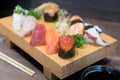 Close-up sushi and sashimi mixed on wooden plate on black wooden Royalty Free Stock Photo