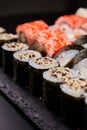 Close up of sushi with sesame seeds wrapped in nori leaves lying on a black board. Royalty Free Stock Photo