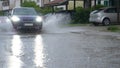CLOSE UP SUV splashes dirty rainwater at camera as it drives through the suburbs