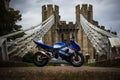 Close-up of a Suzuki motorcycle parked against a backdrop of walking bridge in Conwy, Wales