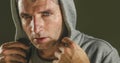 Close up sweaty face portrait of young attractive and fierce looking man wearing hoodie posing in aggressive and defiant attitude