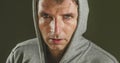 Close up sweaty face portrait of young attractive and fierce looking man wearing hoodie posing in aggressive and defiant attitude