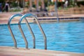 Close up of swimming pool stainless steel handrail descending into tortoise clear pool water. Accessibility of Royalty Free Stock Photo