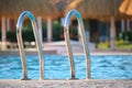 Close up of swimming pool stainless steel handrail descending into tortoise clear pool water. Accessibility of Royalty Free Stock Photo