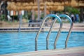 Close up of swimming pool stainless steel handrail descending into tortoise clear pool water. Accessibility of Royalty Free Stock Photo