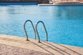 Close up of swimming pool stainless steel handrail descending into tortoise clear pool water. Accessibility of Royalty Free Stock Photo