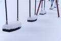 Close up of swings covered in snow at the empty playground in winter Royalty Free Stock Photo