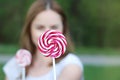 Close Up Swirl Lolipop Holding by a Blured Lovely Young Woman, Blured Green Garden Background. Royalty Free Stock Photo