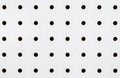 Close-up of symetrical holes on a white pegboard