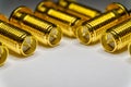 Close-up of symmetric aligned gold plated SMA male connectors electronics components in partial focus white background