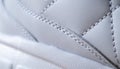 Close-up of synthetic fabric with white diamond stitching and white rubber sole. Sport shoes. Quilted fabric in white or light