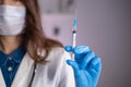 Close-up of a syringe with liquid in the hand of a doctor of a woman in a blue glove Royalty Free Stock Photo