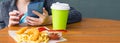 Close-up, on the table is French fries with ketchup, drink and shrimp in batter, in the background a girl with a phone in her Royalty Free Stock Photo