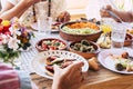 Close up of table full of fresh vegetarian vegan food with group of people eating together in friendship or parentship at home or Royalty Free Stock Photo