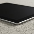A close-up of a tablet device placed on a textured light gray surface. The tablet has a Royalty Free Stock Photo