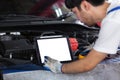 Close up Tablet empty white screen, Repairman auto mechanic using tablet white screen to check for damage inside engine.