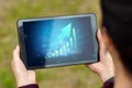 Close-up of a tablet in hands with the image of a graph with an upward arrow. New technologies. Copy space