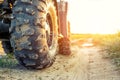 Close-up tail view of ATV quad bike on dirt country road at evening sunset time. Dirty wheel of AWD all-terrain vehicle. Travel