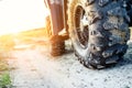 Close-up tail view of ATV quad bike on dirt country road at evening sunset time. Dirty wheel of AWD all-terrain vehicle. Travel