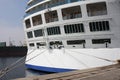 Close-up tail view of big modern white cruise ship liner morred with mooring cable at cargo port of sea or ocean Royalty Free Stock Photo