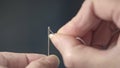 Close-up of a tailor`s hands inserting a thread into the eye of a needle. Repair of clothes at home