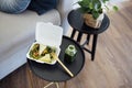 Close up of take away food in white container with wooden fork and plactic bottle of green smoothie