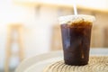 Close up of take away plastic cup of iced black coffee Americano on table in restaurant Royalty Free Stock Photo