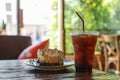 Close up of takeaway plastic cup of iced black coffee Americano with piece of Banoffee on wooden table cake pie in restaurant Royalty Free Stock Photo