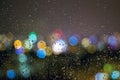 Blurred lights of city night view from behind glass with raindrops Royalty Free Stock Photo