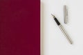 Burgundy color,hardcover annual agenda on the white surface with stylographic pen Royalty Free Stock Photo