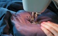 Close-up of talor`s hands sews to blue jacket leather inserts on sewing mashine.