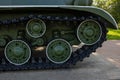 Close-up of the tank chassis. The iron wheels and tracks of the tank`s undercarriage are painted green and black