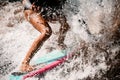 Close-up of tanned legs of sporty woman who actively riding on surf style wakeboard. Royalty Free Stock Photo