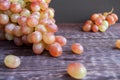 Close-up tassel of ripe green-red grapes and some berries are lying on the dark wooden table. Royalty Free Stock Photo