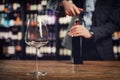 Close-up tasting glass goblet in background of sommelier opens with corkscrew cork of bottle of red wine