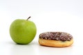 Close-up of tasty chocolate donut and fresh green apple on white background suggesting healthy eating concept Royalty Free Stock Photo