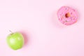 Close-up of tasty donuts and fresh green apple on pink background suggesting healthy food concept Royalty Free Stock Photo