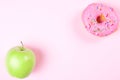 Close-up of tasty donuts and fresh green apple on pink background suggesting healthy food concept Royalty Free Stock Photo