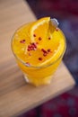 Close-up of a tasty drink with turmeric, honey, ginger and orange topped with pink pepper corns