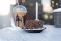 Frappuccino, small chocolate cake, and coffee cup on round gray table