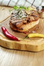 Close up on tasty Grilled Pork neck served on pita bread with onion, microgreen and hot pepper. Wooden background. Copy space. Royalty Free Stock Photo