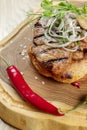 Close up on tasty Grilled Pork neck served on pita bread with onion, microgreen and hot pepper. Wooden background. Copy space. Royalty Free Stock Photo