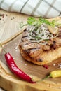 Close up on tasty Grilled Pork neck served on pita bread with onion, microgreen and hot pepper. Wooden background. Copy space. Royalty Free Stock Photo