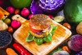 Close-up of tasty, home-made vegan hamburger on wooden table with fresh vegetables around Royalty Free Stock Photo