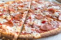 Close Up of Tasty Hot Pizza with Bacon, pepperoni sausage, ham, mozzarella cheese, sweet pepper, herbs, red onion. Food to order Royalty Free Stock Photo