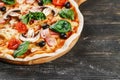 CLOSE-UP Tasty Italian Hot Pizza on dark wooden table with mushrooms, basil, tomato, olives and cheese. Look as Prosciutto,