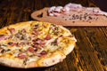 Close up of tasty pizza on wooden table, near lie cutting board Royalty Free Stock Photo